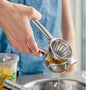 Hand using a metal lemon squeezer with a blurred background